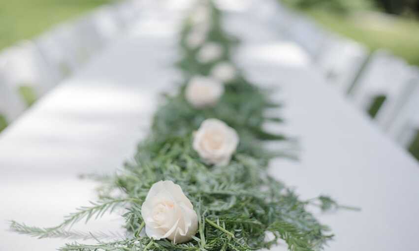 Long white table with green and white floral centerpiece 